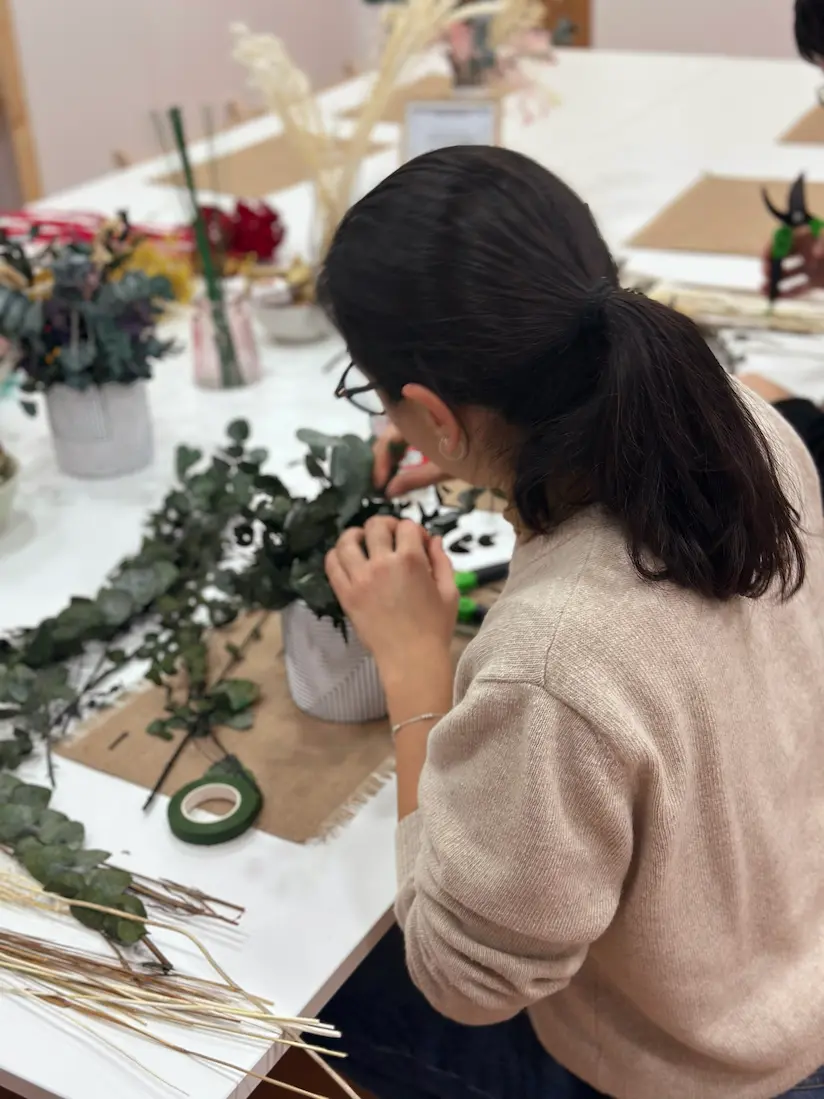 mujer haciendo un arreglo floral en un taller de flores preservadas en maceta