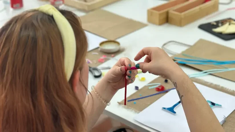 mujer enrollando papel en un taller de letras de quilling para adultos